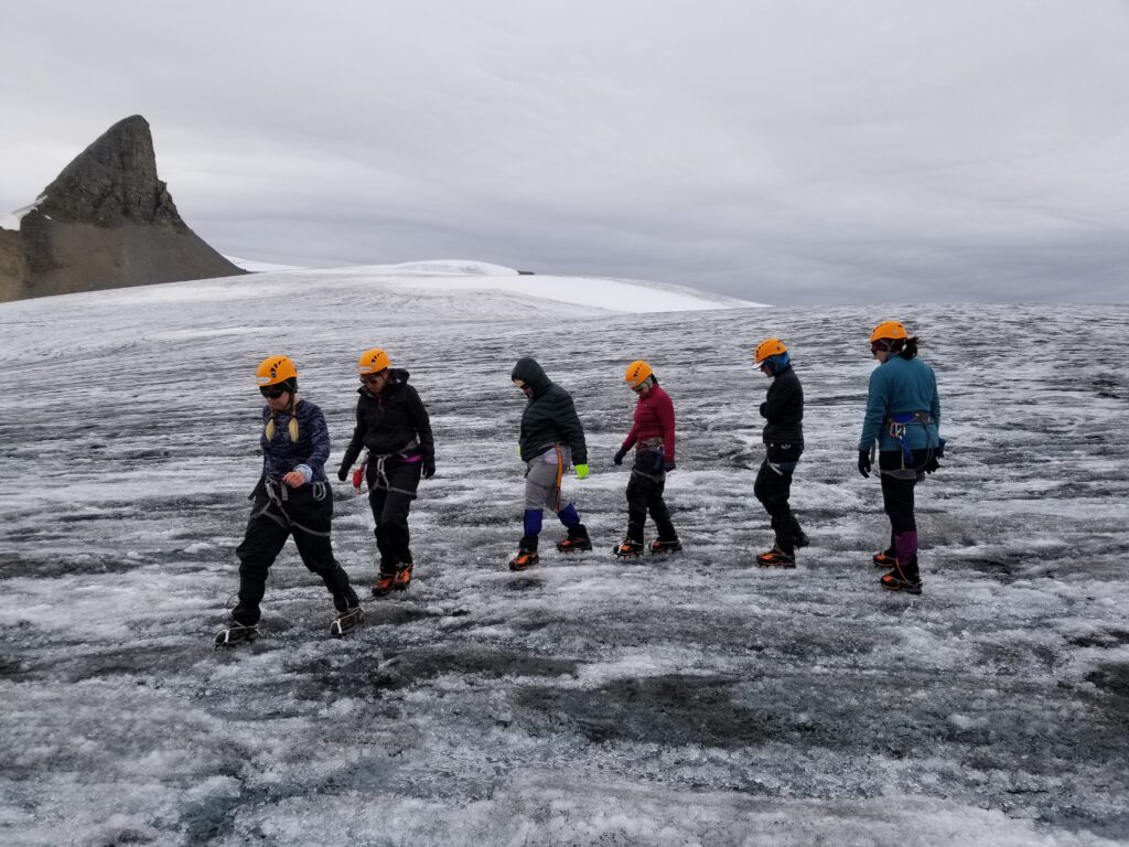 A group of Explorer Chick women hike on a glacier