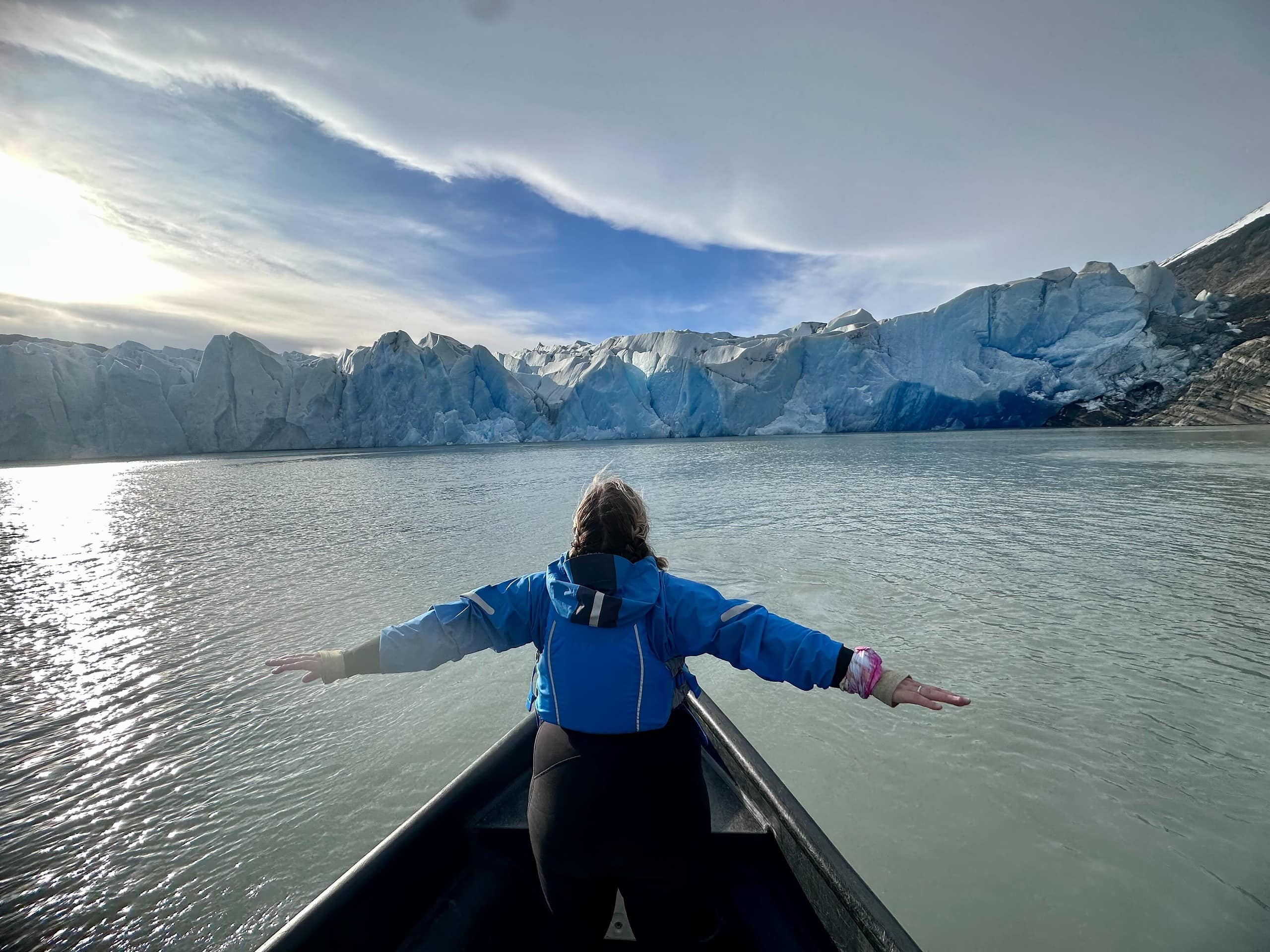 An explorer chick woman with her arms stretched out at the front of a boat