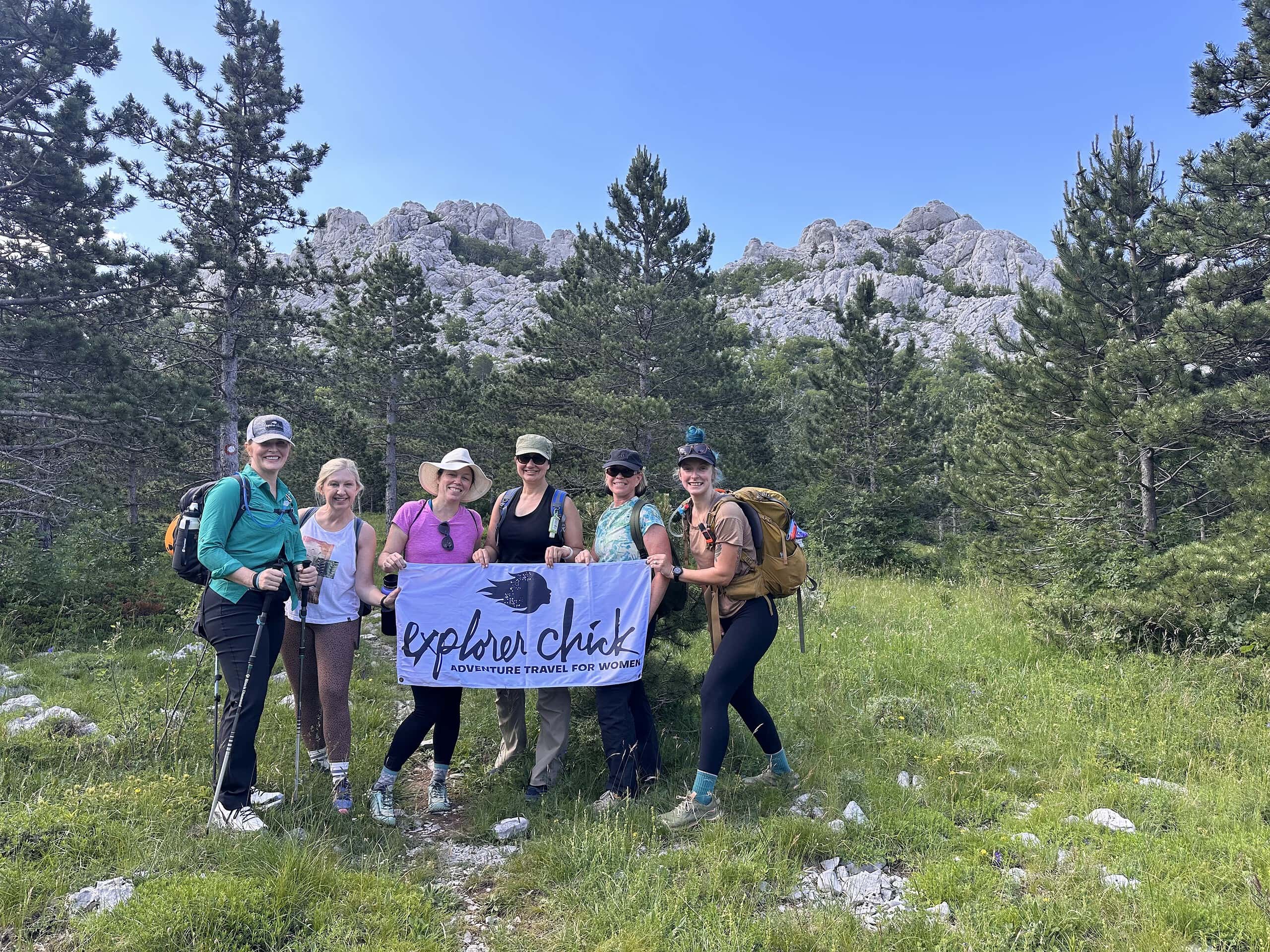 A group of women hiking holding a sign that says Explorer Chick