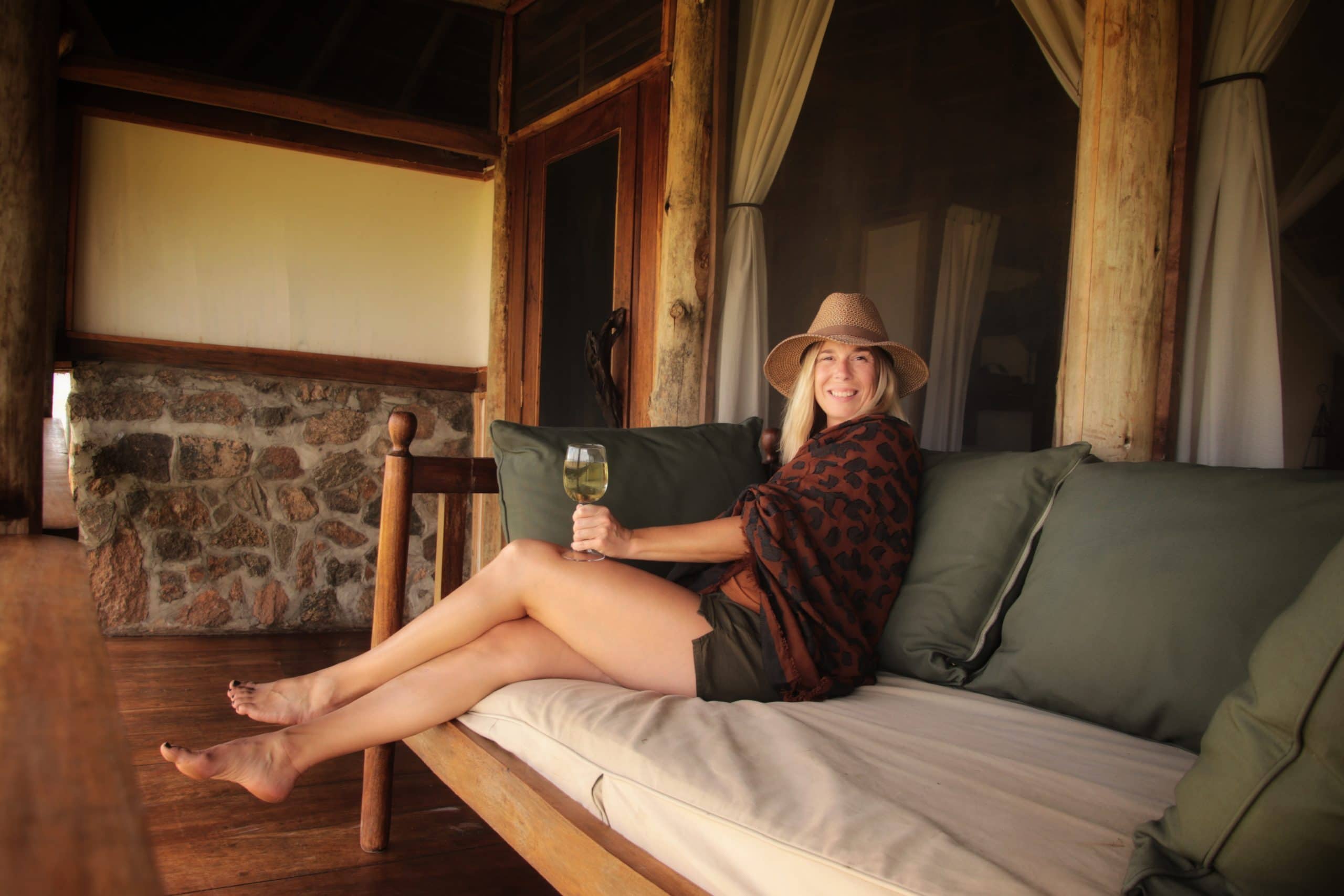 Explorer Chick Founder Nicki Bruckmann holds a glass of wine while on safari in Uganda