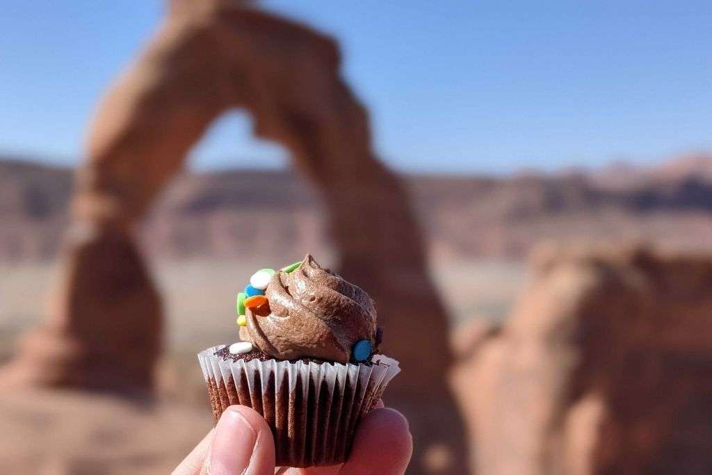 A hand holding a cupcake in the Arches National Park