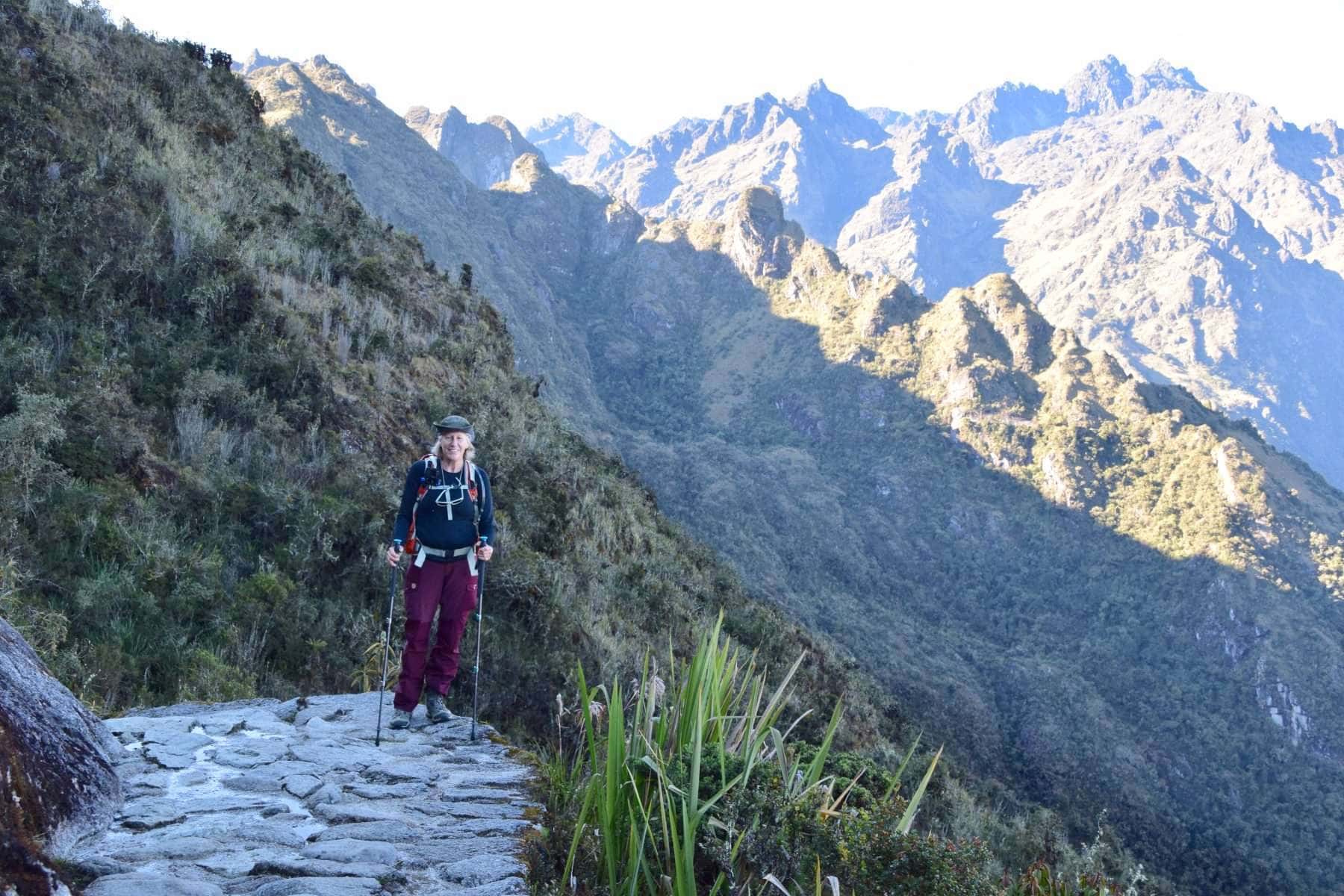 Woman standing on the Inca Trail in hiking gear posing in front of a mountain