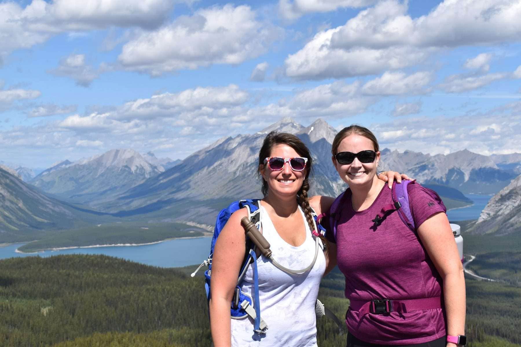 Two women posing in front of mountains and a river during a hike near Banff, Canada