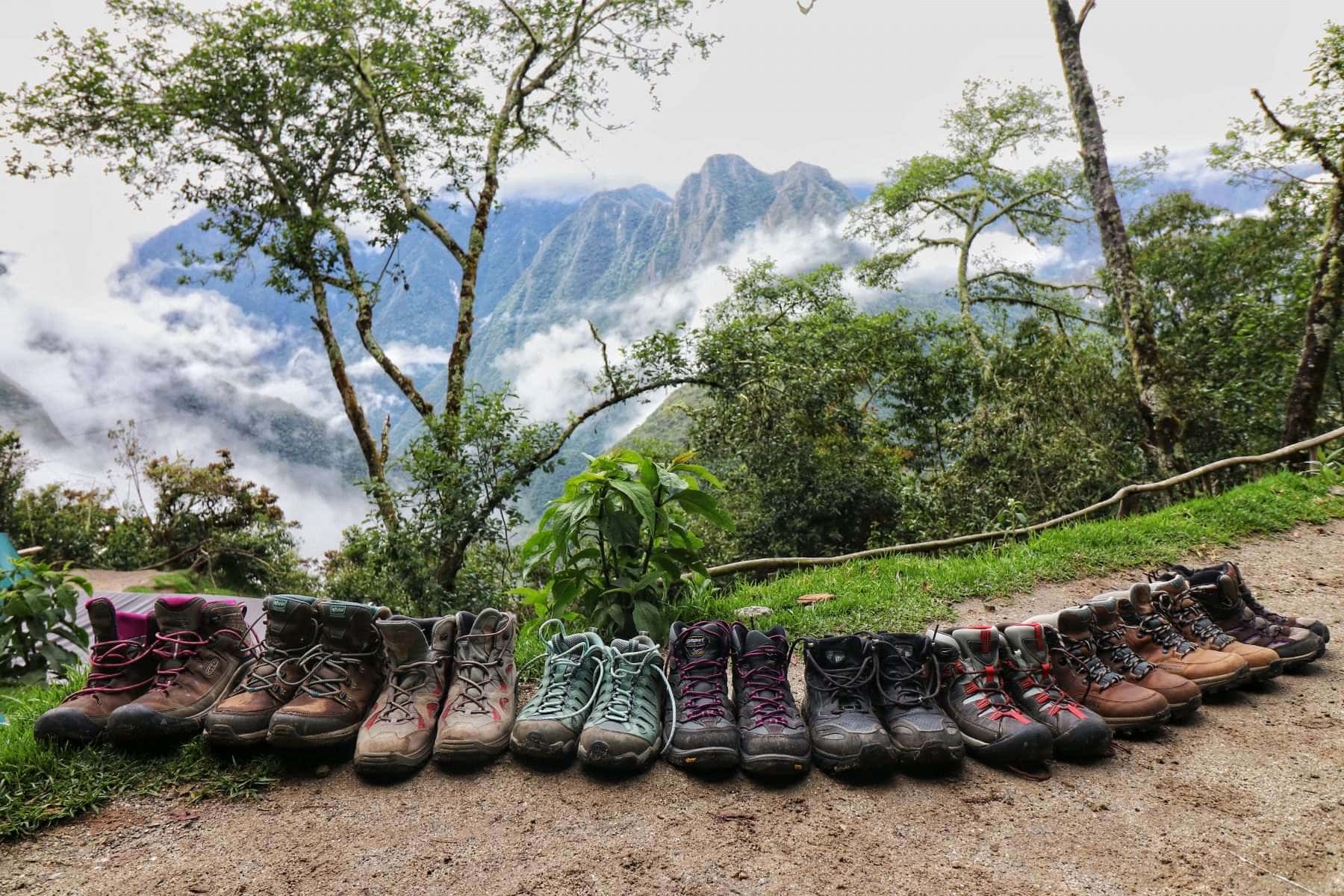 Hiking boots lined up along the Inca Trail with trees and mountains in the distance