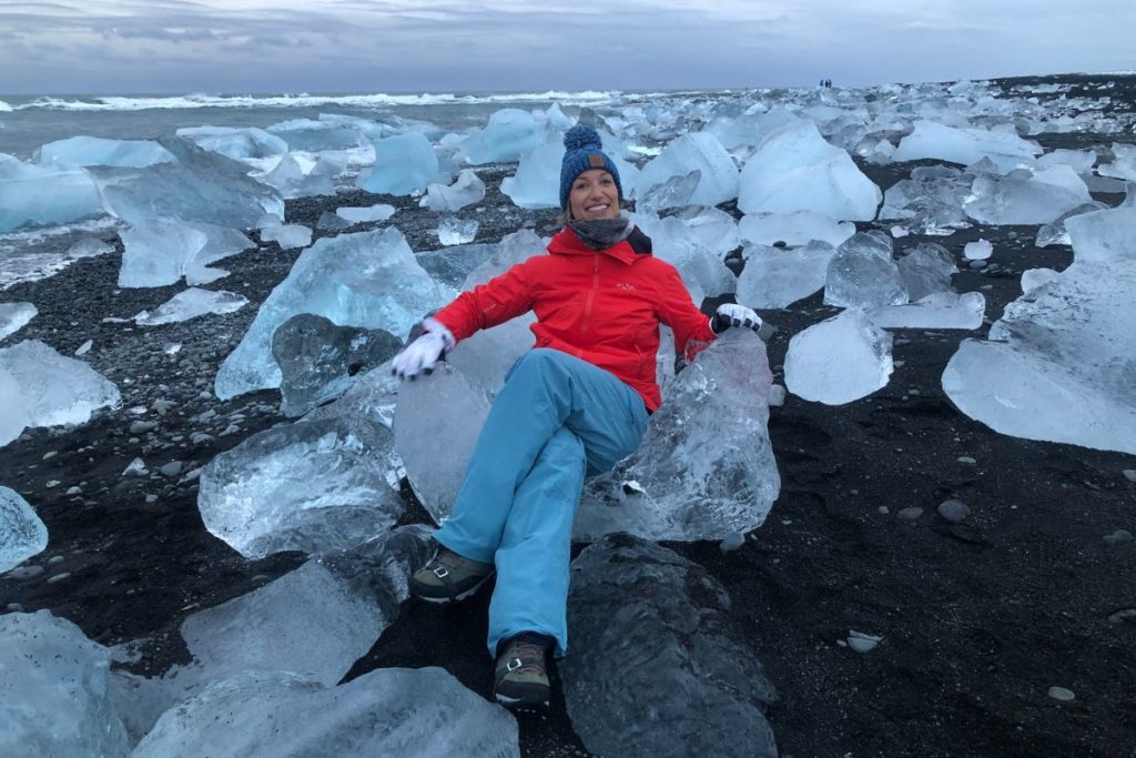 A woman sits on a glacier rock in Iceland