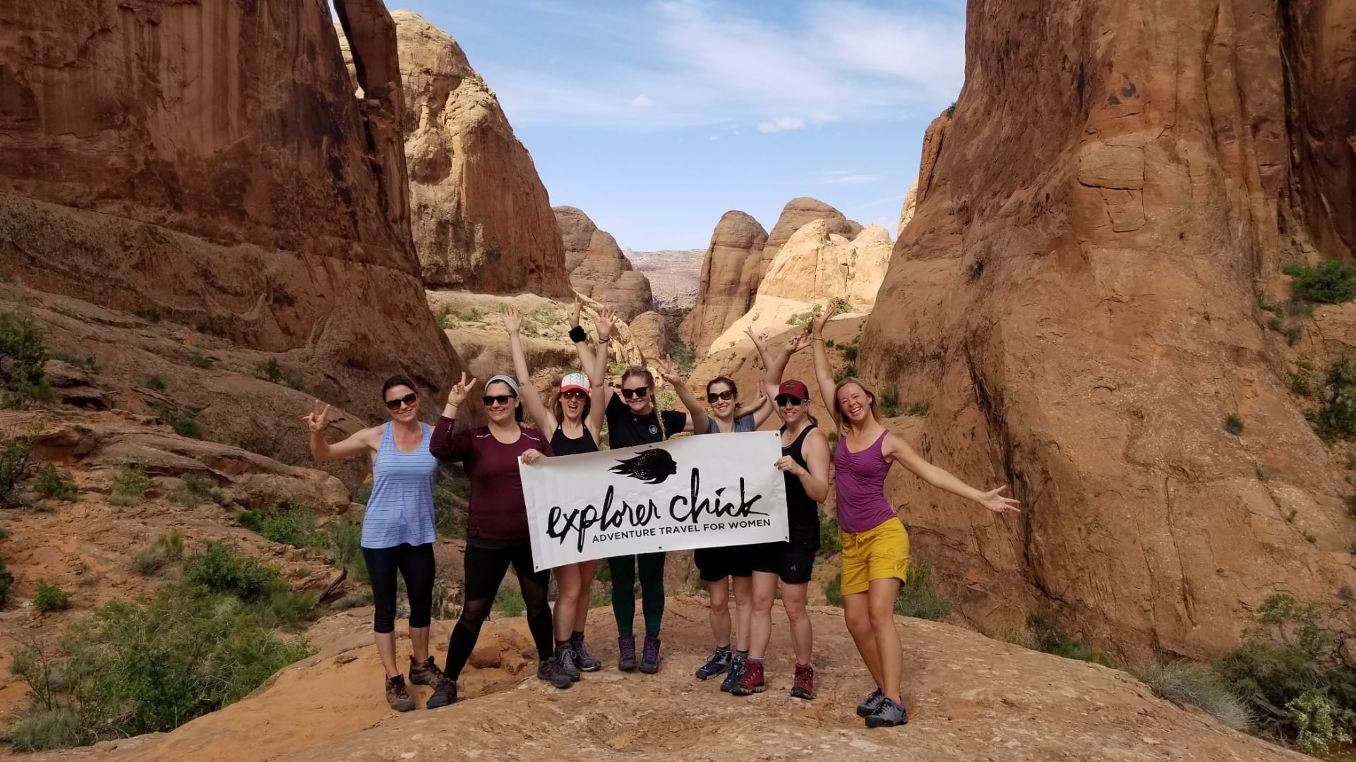 A group of Explorer Chick women hiking in a slot canyon in Moab Utah
