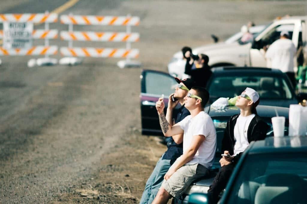 people lean against their car watching the 2017 solar eclipse