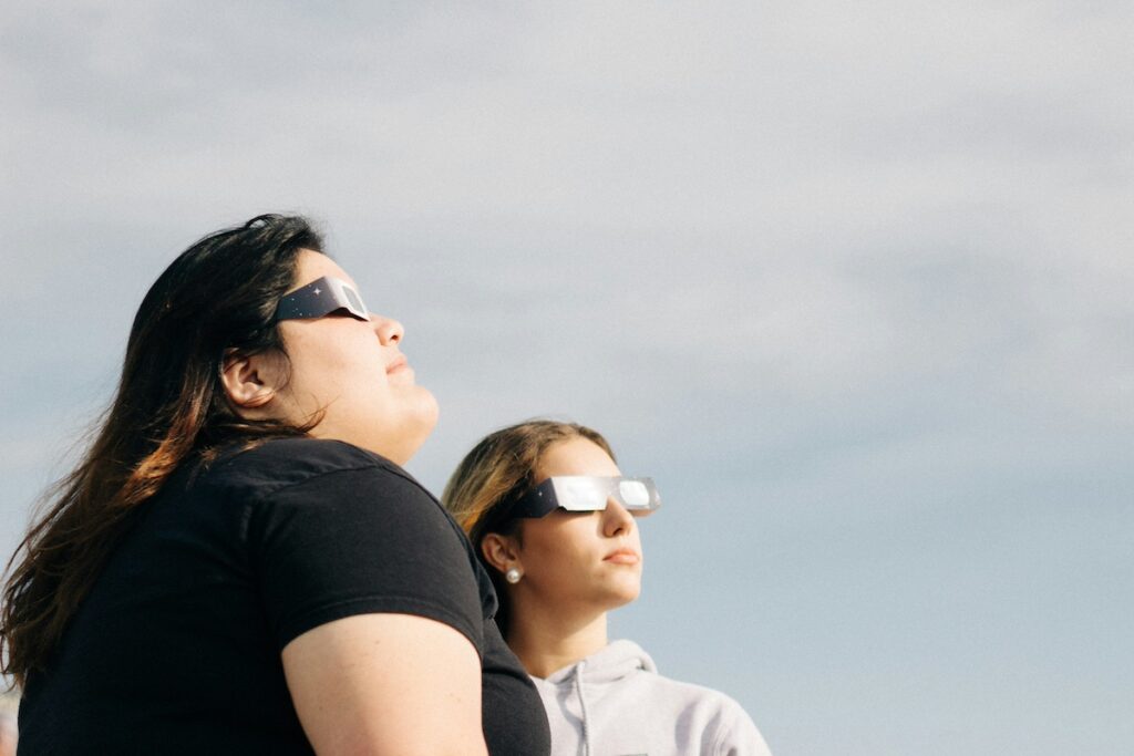 Two women stand facing the total solar eclipse