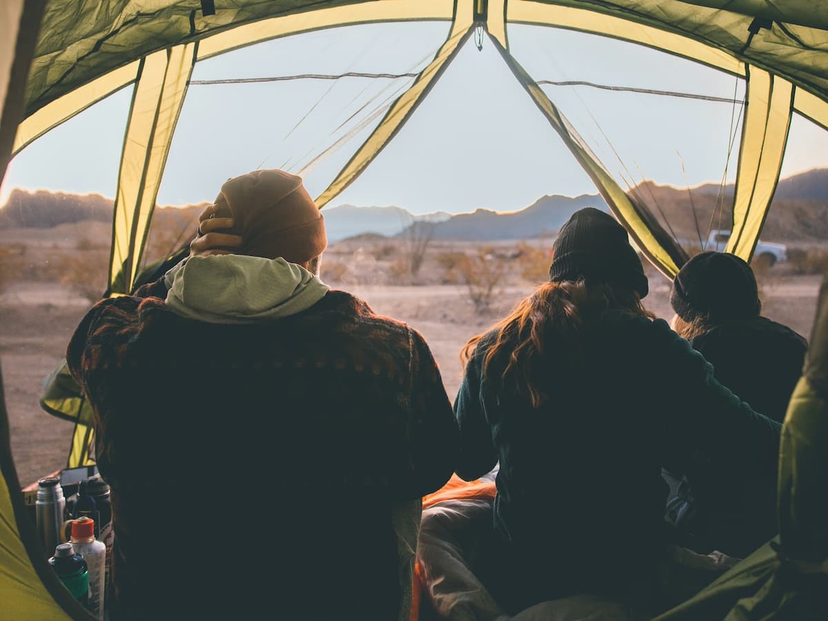 two people sitting in a camping tent looking out at the scenery