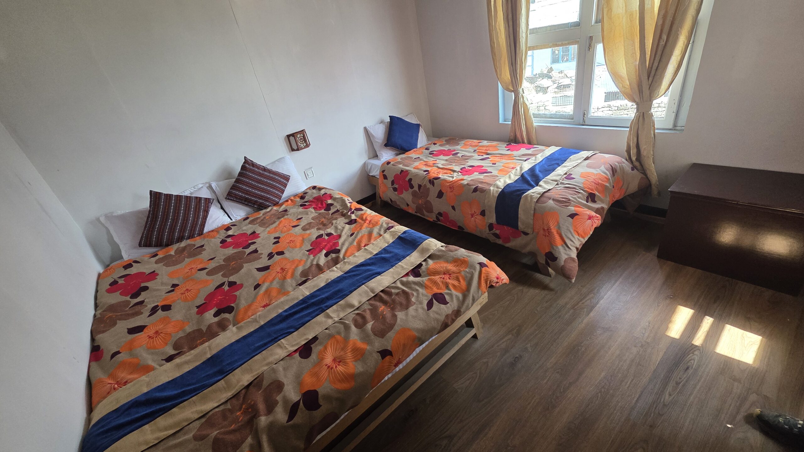 Cozy teahouse room on the Everest Base Camp trek with twin beds, warm blankets, and mountain village views.