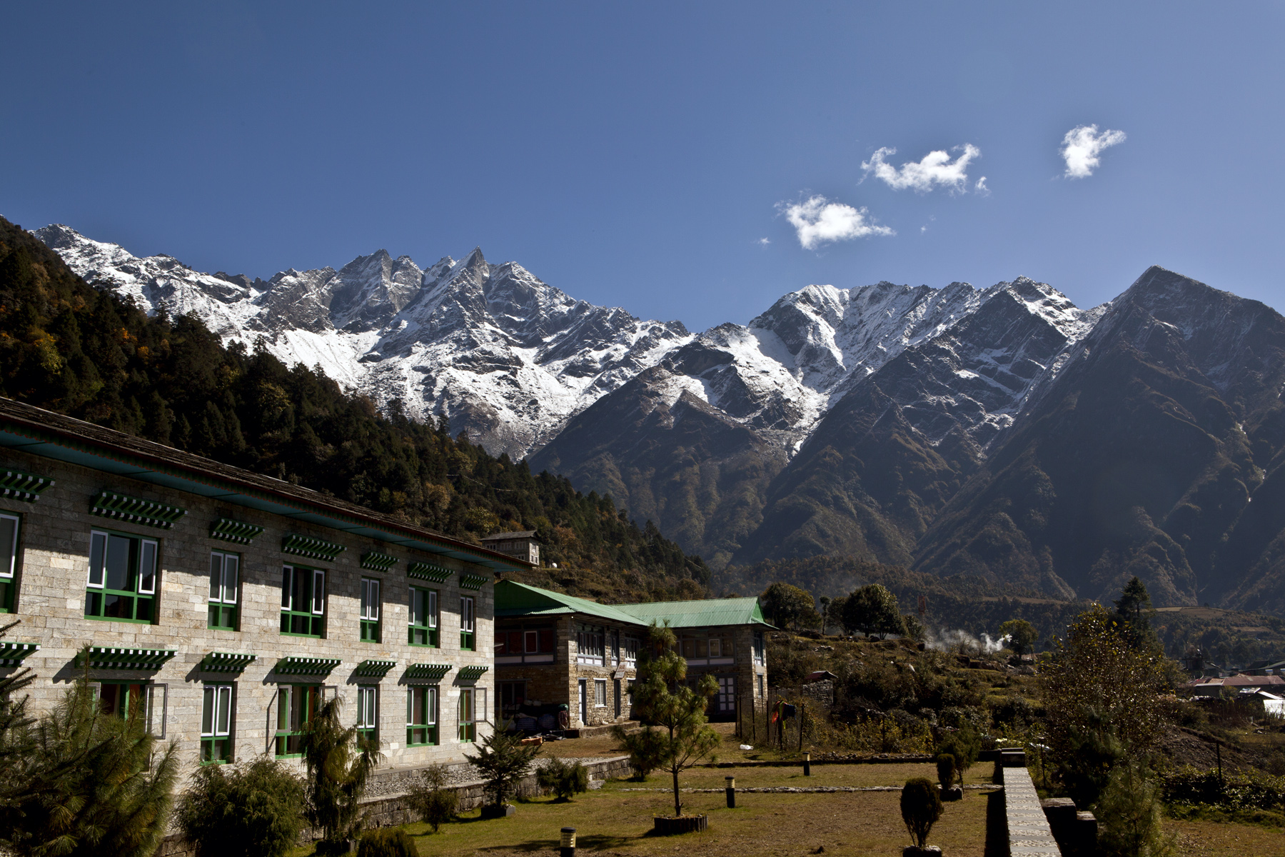 Luxury tea house in Lukla, Nepal with green-roofed lodge and panoramic views of snow-capped Himalayas at the start of the Everest Base Camp trek.