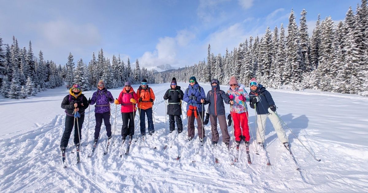 Explorer Chick women’s group cross-country skiing in Banff National Park during a winter adventure with snowy trails and mountain forest scenery